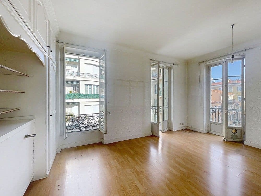Living room with wooden floor and French windows to balconies, 1-bedroom apartment in the Carré d’Or, Nice