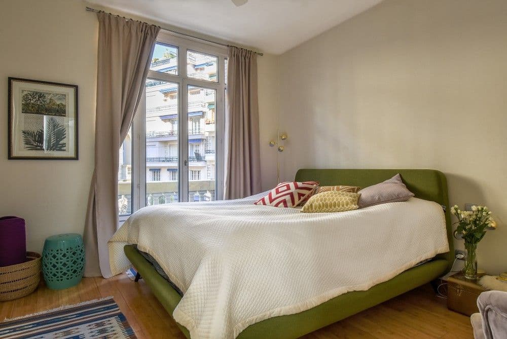 Bedroom with green upholstered bed and tall window, 2-bedroom apartment in the Carré d’Or, Nice