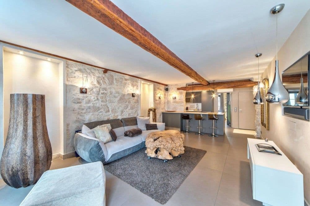 Living room with stone wall, sofa and kitchen behind, 1-bedroom apartment in the Port, Nice