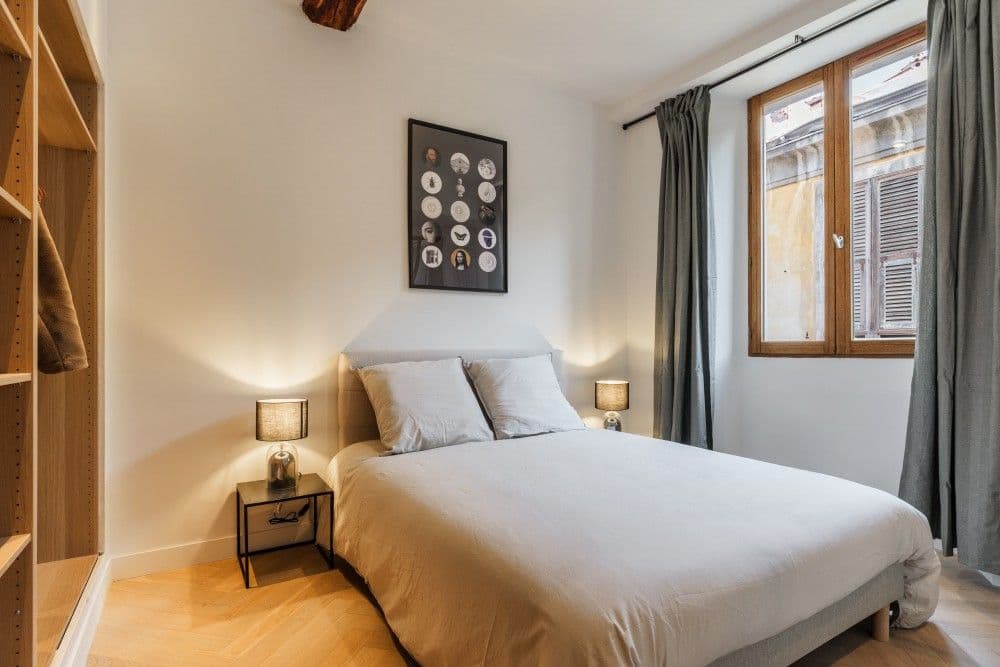 Bedroom with bedside lamps and wooden-framed window, 2-bedroom apartment in the Old Town, Nice