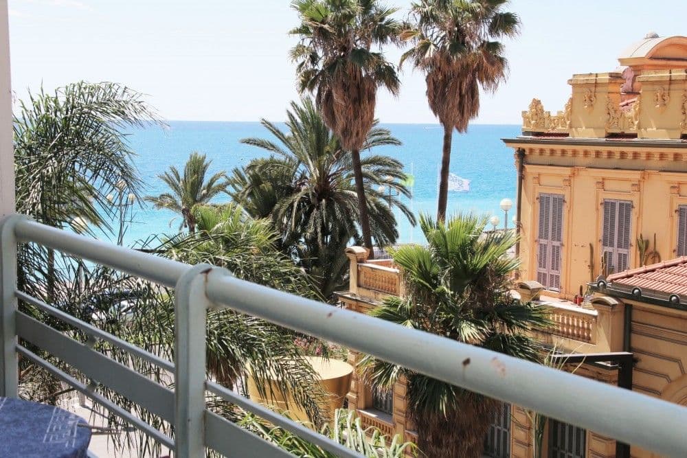 Balcony view through palm trees to the sea and a Belle Époque villa, 2-bedroom apartment in the Promenade des Anglais, Nice