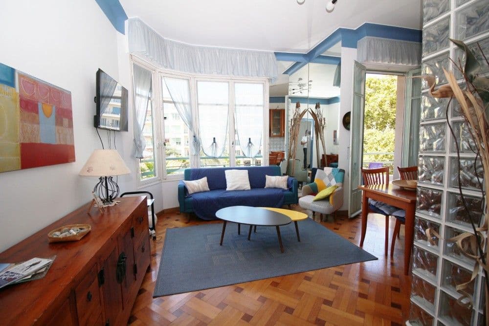 Living room with blue sofa, bay window and parquet floor, 2-bedroom apartment in the Promenade des Anglais, Nice