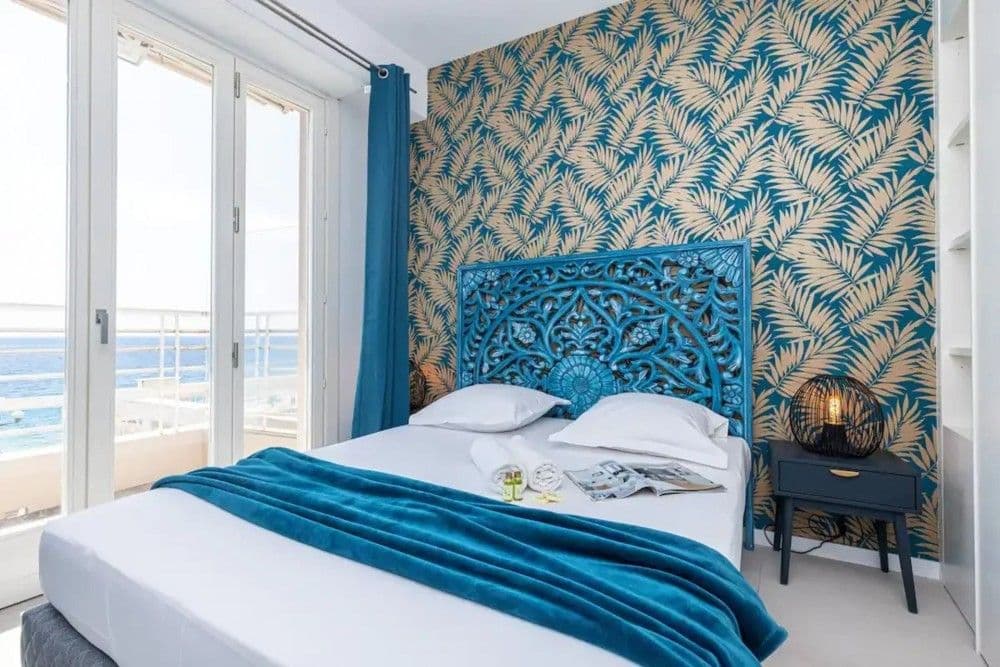 Bedroom with carved headboard and palm-leaf wallpaper, 2-bedroom apartment in the Promenade des Anglais, Nice