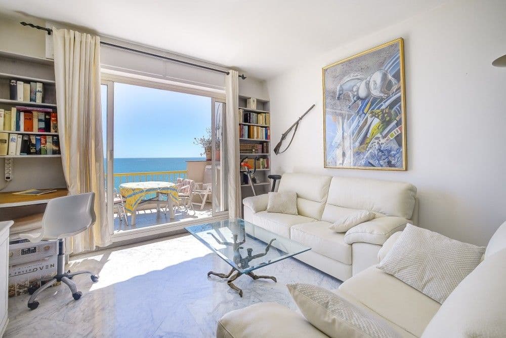 Living room with white sofas and sliding doors to the sea-view balcony, 2-bedroom apartment in the Promenade des Anglais, Nice