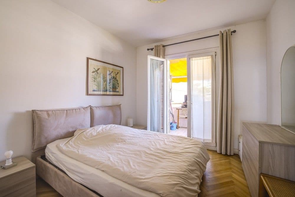 Bedroom with upholstered bed and French window, 2-bedroom apartment in the Promenade des Anglais, Nice