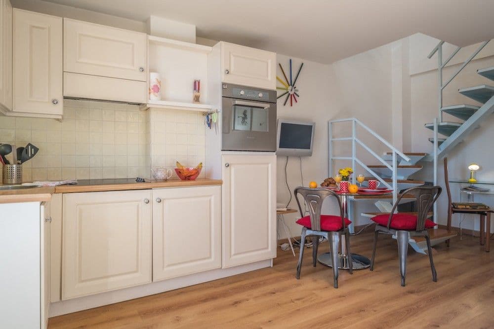 Kitchen with cream units, dining table and spiral staircase, 1-bedroom apartment in the Carré d’Or, Nice