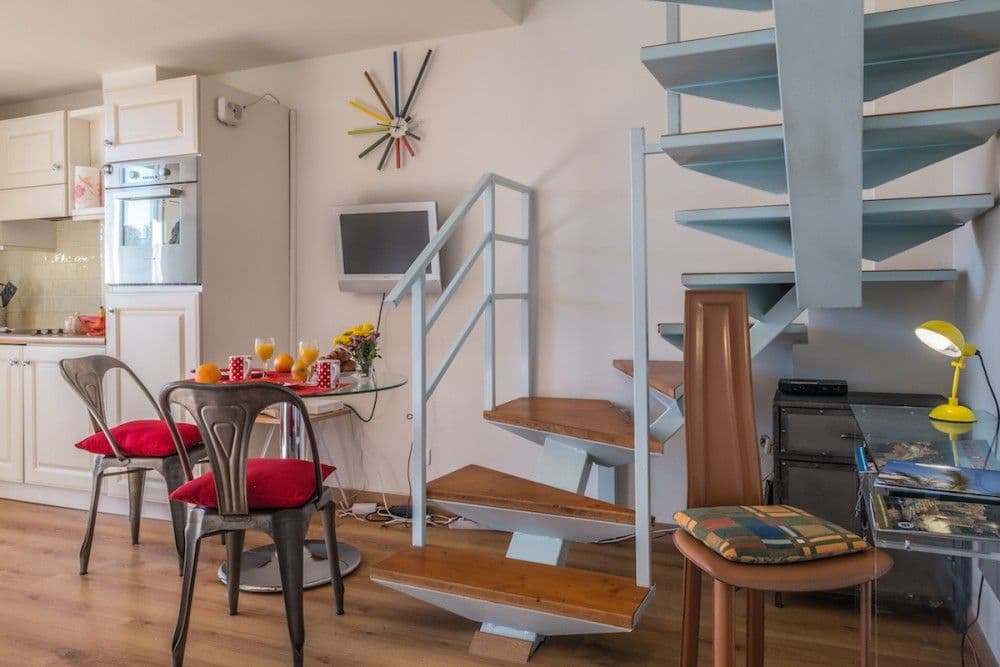 Dining table beside the spiral staircase, 1-bedroom apartment in the Carré d’Or, Nice