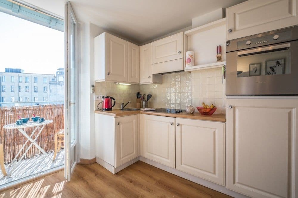 Kitchen with cream units and door to the balcony, 1-bedroom apartment in the Carré d’Or, Nice
