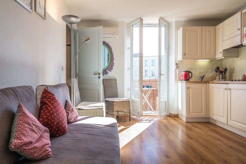 Living room with sofa and open kitchen, 1-bedroom apartment in the Carré d’Or, Nice
