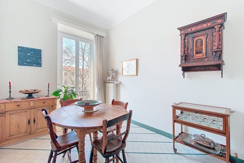 Dining room with round table and tall window, 3-bedroom apartment in central Nice