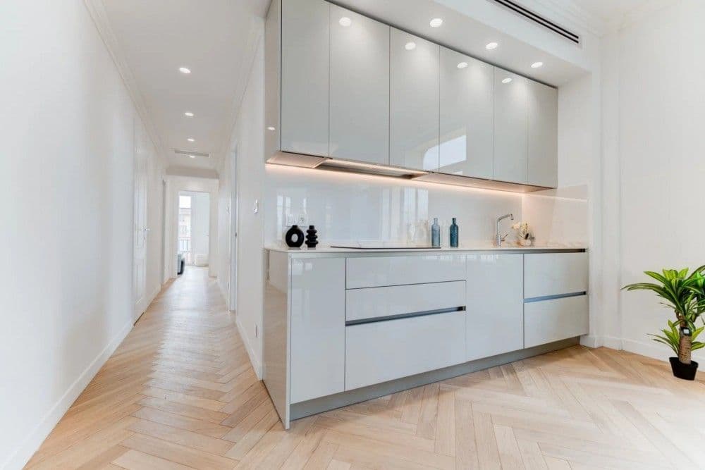 Fitted kitchen with white gloss units along the hallway, 3-bedroom apartment in the Carré d’Or, Nice
