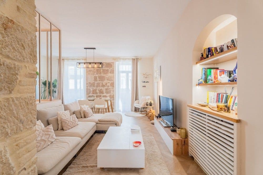 Living room with exposed stone, sofa and built-in shelving, 3-bedroom apartment in the Port, Nice