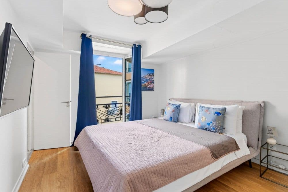 Bedroom with blue curtains and window onto the square, 2-bedroom apartment in the Old Town, Nice