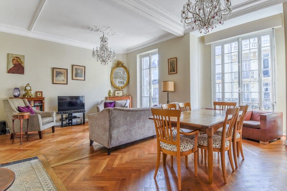 Living and dining room with herringbone parquet, chandeliers and tall windows, 2-bedroom apartment in the Carré d’Or, Nice