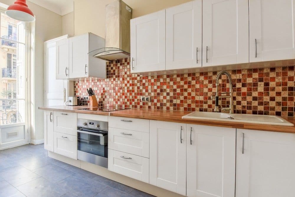 Fitted kitchen with white cabinets and terracotta mosaic splashback, 2-bedroom apartment in the Carré d’Or, Nice