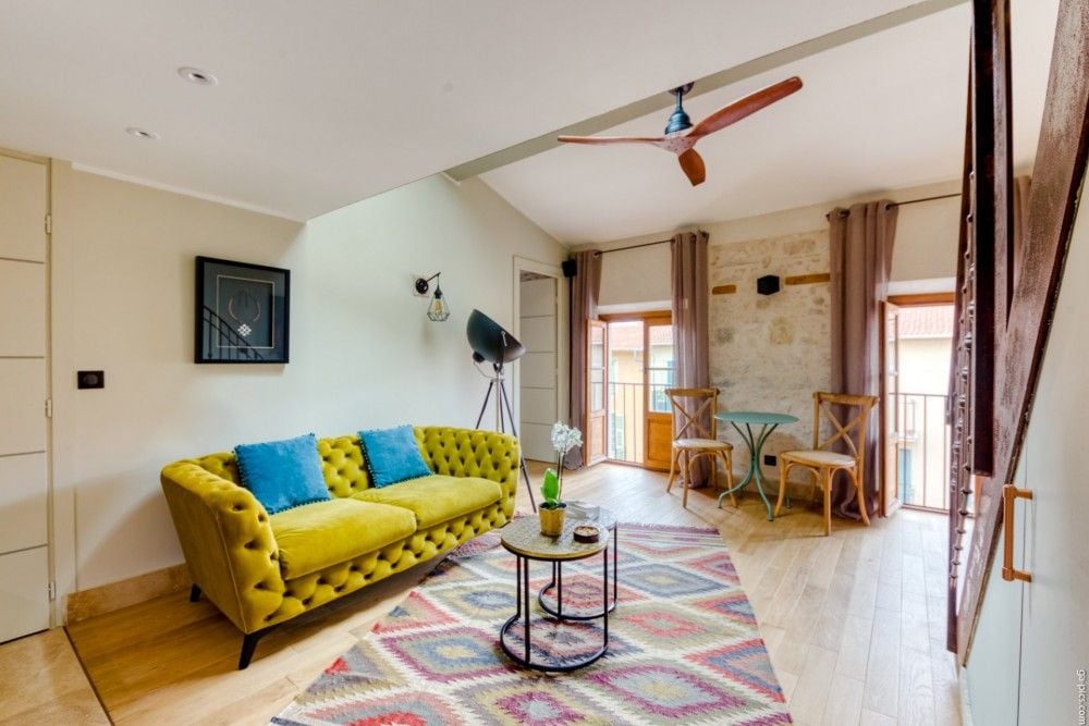 Loft living room with exposed stone wall, mezzanine and colourful rug, 2-bedroom apartment in the Port, Nice