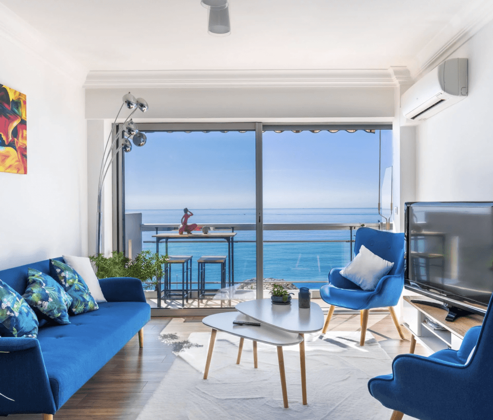 Living room with blue sofa and sliding doors to a sea-view balcony, 2-bedroom apartment in Cagnes-sur-Mer