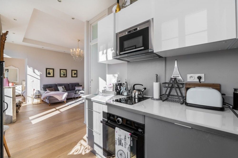 Kitchen with white units and view through to the living room, 2-bedroom apartment in central Nice