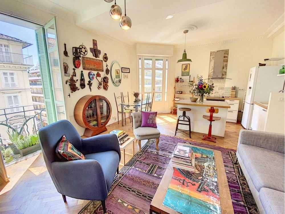 Living room with colourful art, armchairs and kitchen beyond, 2-bedroom apartment in the Port, Nice