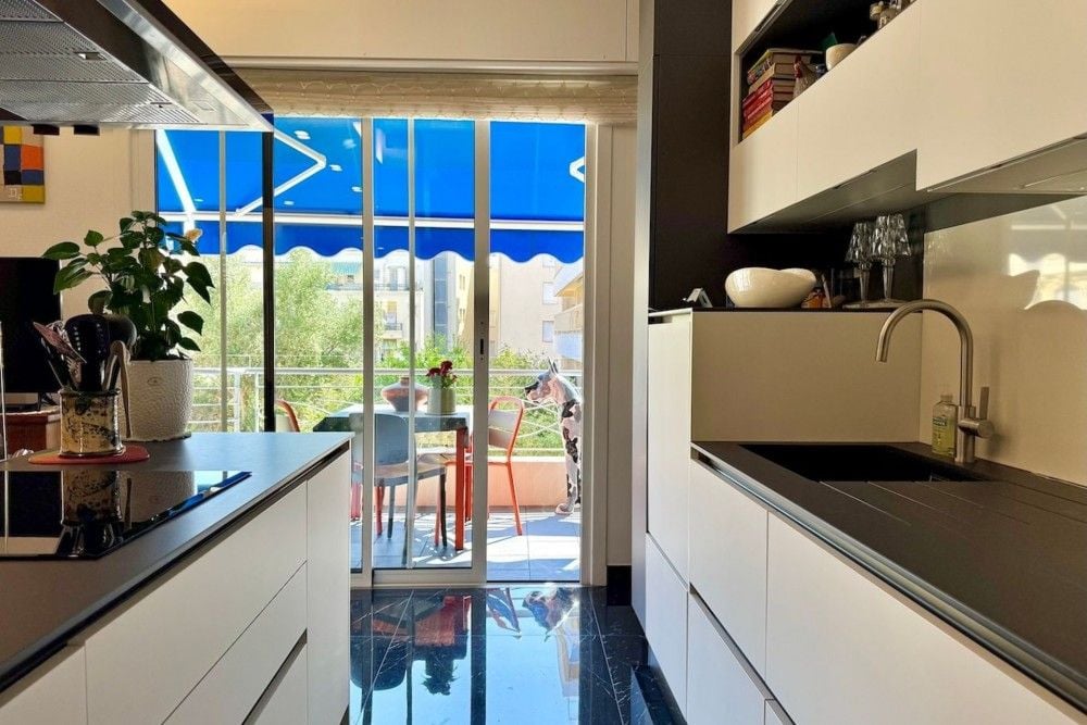 Kitchen with white units and doors to the balcony, 2-bedroom apartment in the Carré d’Or, Nice