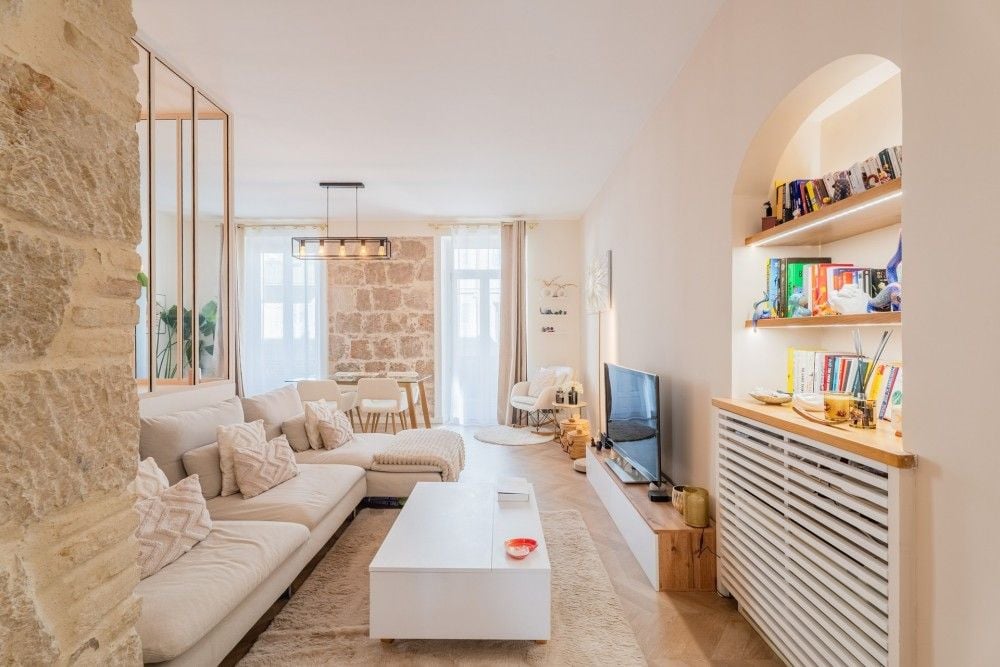 Living room with exposed stone, sofa and built-in shelving, 3-bedroom apartment in the Port, Nice