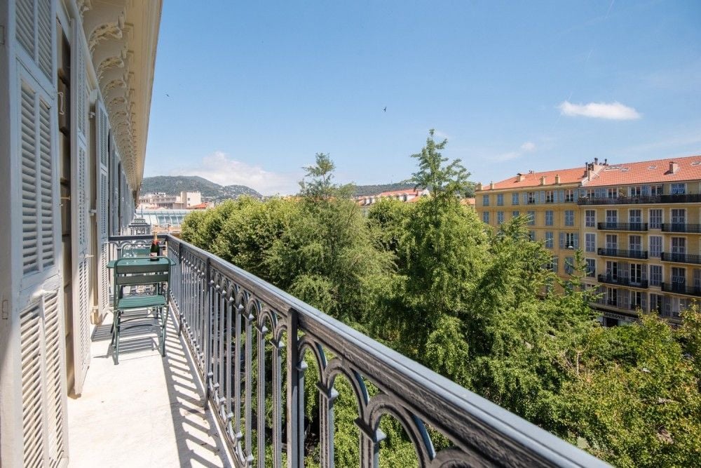 A wrought-iron balcony above the trees and façades of the Wilson quarter