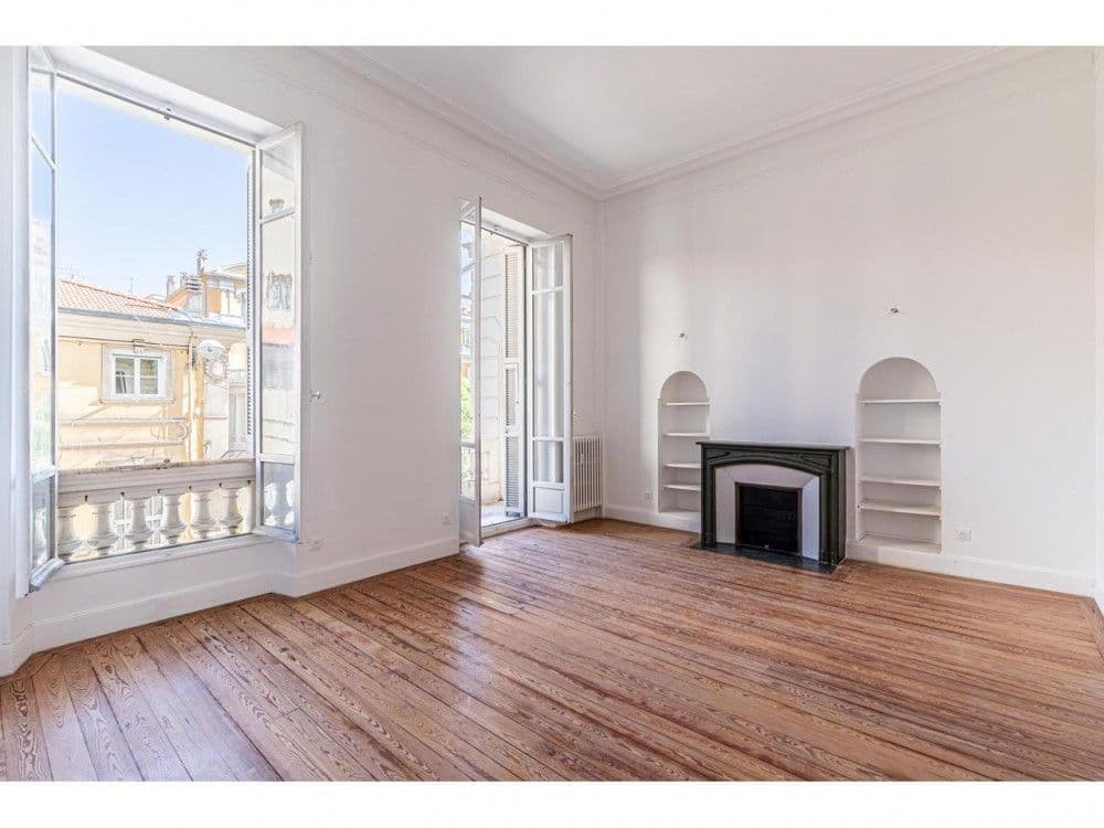 Room with fireplace, alcove shelves and French window to a balcony, 3-bedroom apartment in the Carré d’Or, Nice