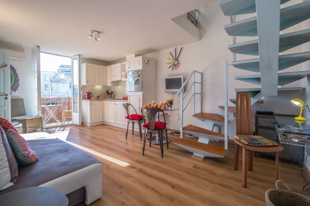 Duplex living room with spiral staircase and open kitchen, 1-bedroom apartment in the Carré d’Or, Nice