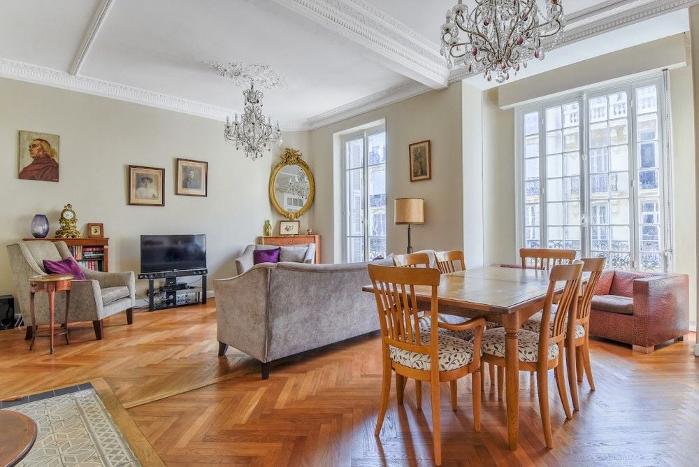 Living and dining room with herringbone parquet, chandeliers and tall windows, 2-bedroom apartment in the Carré d’Or, Nice
