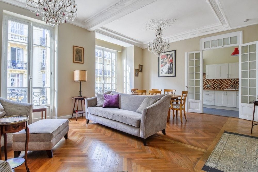 Living room with herringbone parquet, chandeliers and a view through to the kitchen, 2-bedroom apartment in the Carré d’Or, Nice