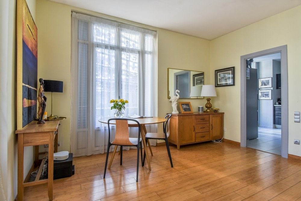 Dining area with wooden floor, tall window and sideboard, 2-bedroom apartment in the Carré d’Or, Nice