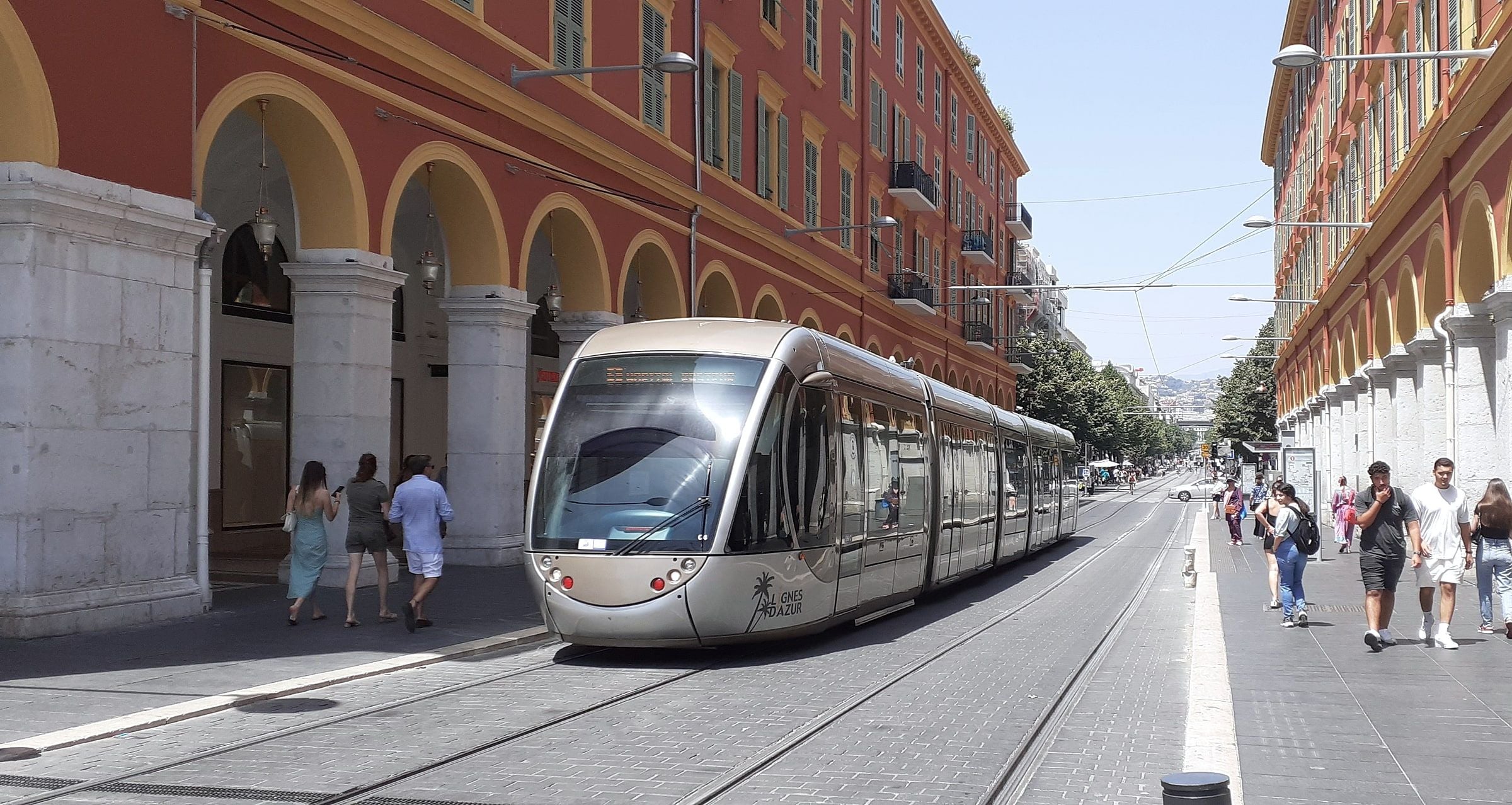 A tram passing the red arcades of Avenue Jean Médecin in central Nice
