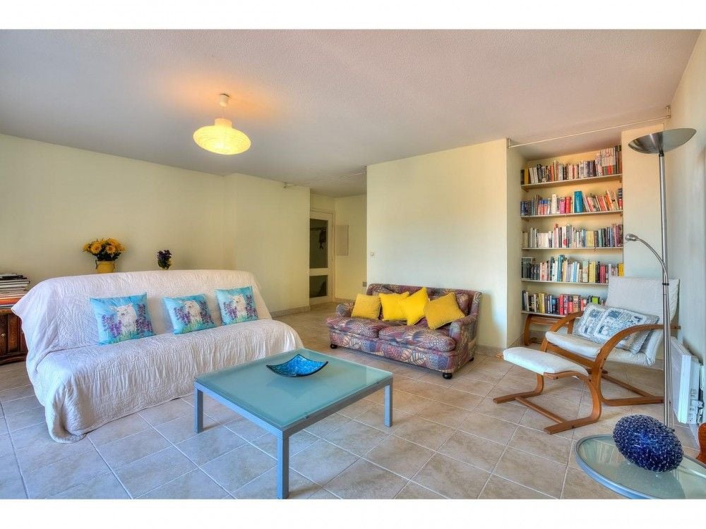 Living room with bookshelves, sofa and tiled floor, 2-bedroom apartment in the Old Town, Nice