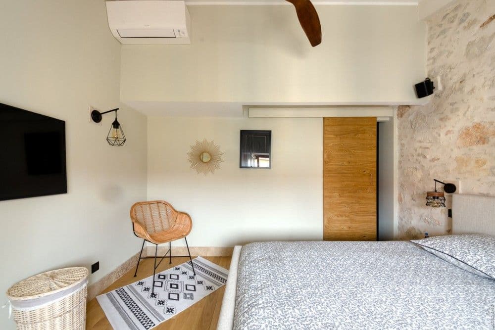 Bedroom with exposed stone wall and wooden sliding door, 2-bedroom apartment in the Port, Nice
