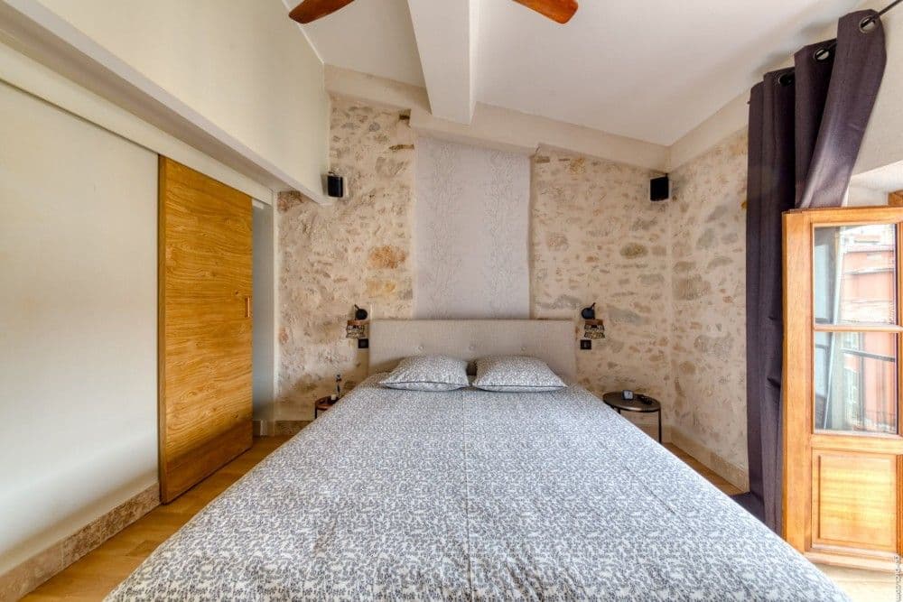 Bedroom with exposed stone wall and French window, 2-bedroom apartment in the Port, Nice