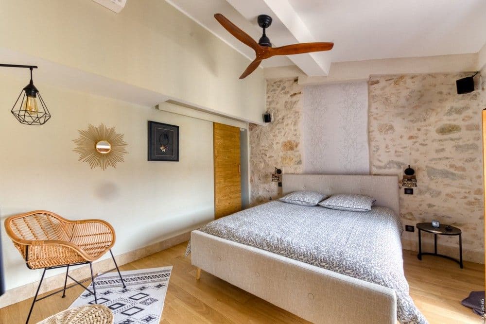 Bedroom with ceiling fan, rattan chair and stone wall, 2-bedroom apartment in the Port, Nice