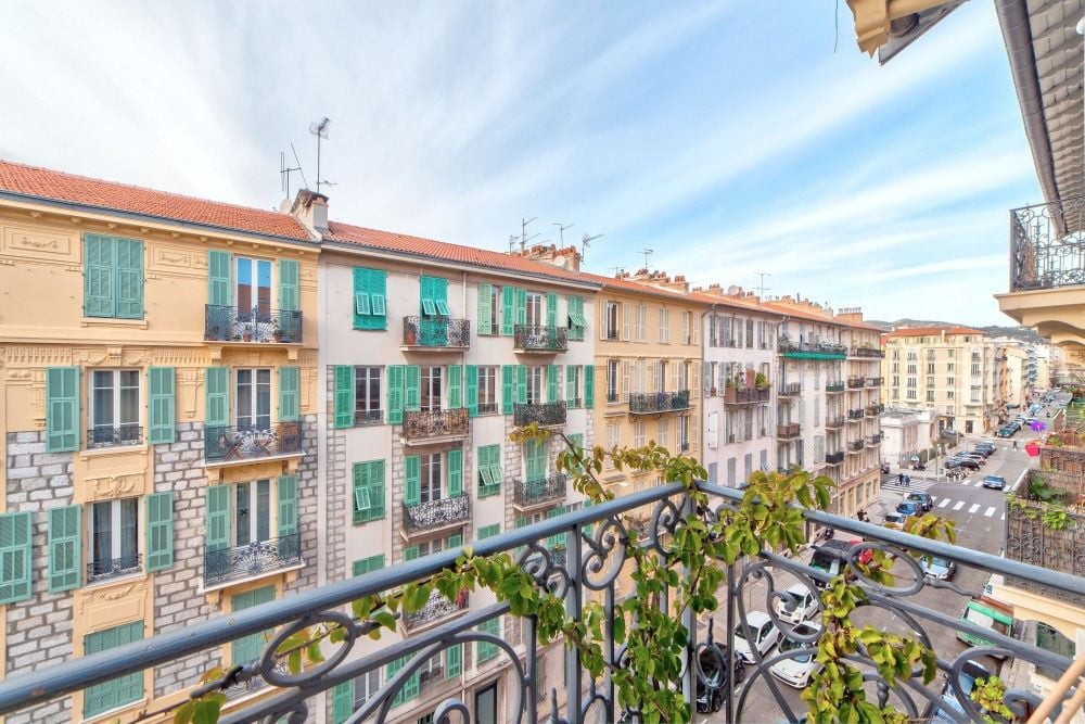 Balcony with wrought-iron railing and a view down a street of pastel façades, 2-bedroom apartment in the Port, Nice