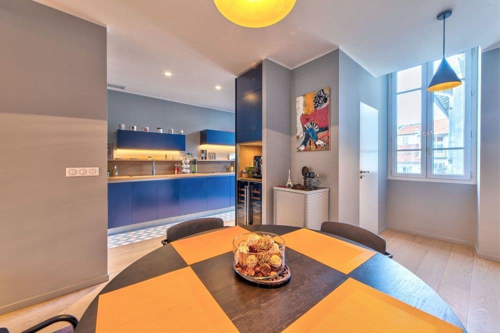 Dining area with round table, open kitchen and tall window, 2-bedroom apartment in the Port, Nice