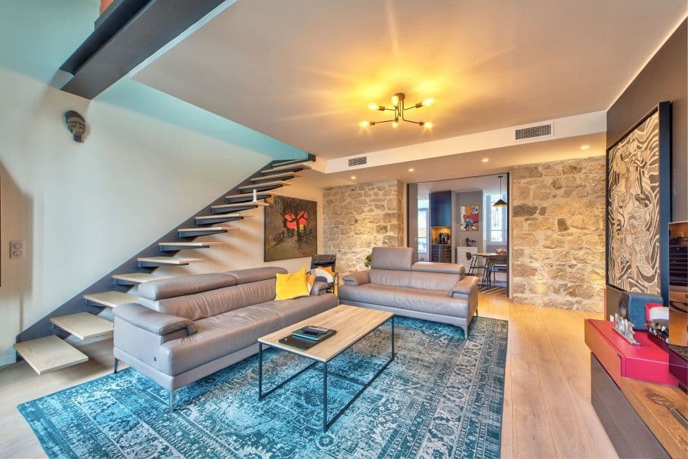 Living room with leather sofas, stone wall and floating staircase, 2-bedroom apartment in the Port, Nice