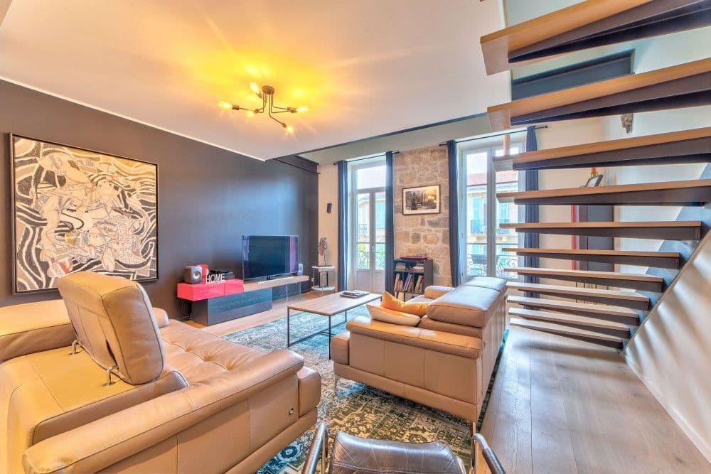 Living room with leather sofas, artwork and floating staircase, 2-bedroom apartment in the Port, Nice