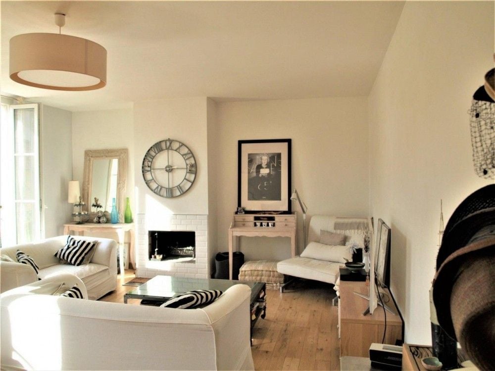 Living room with fireplace, white sofas and oak floor, 2-bedroom apartment in the Carré d’Or, Nice