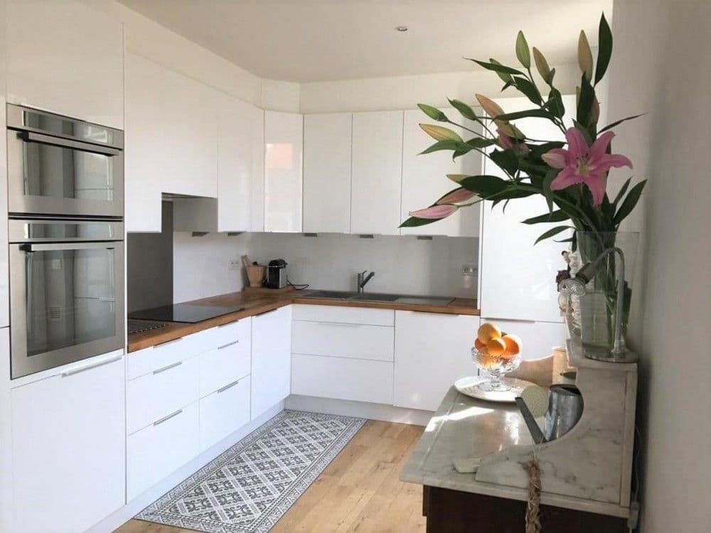 White fitted kitchen with built-in ovens and oak worktop, 2-bedroom apartment in the Carré d’Or, Nice