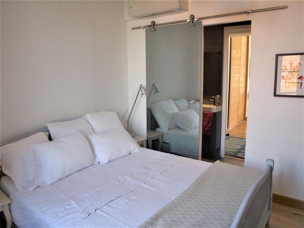 Bedroom with sliding barn door to the bathroom, 2-bedroom apartment in the Carré d’Or, Nice