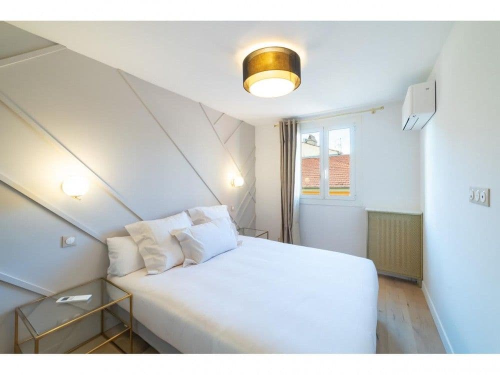 Bedroom with panelled headboard wall and window over the rooftops, 2-bedroom apartment in the Old Town, Nice