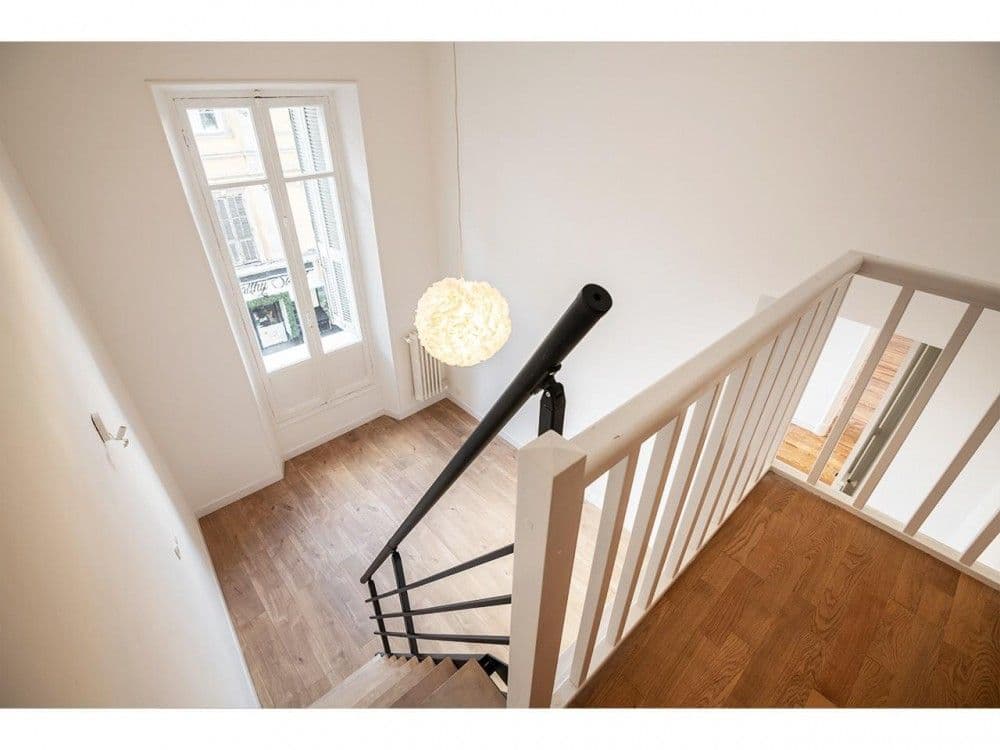 Staircase with white banister and tall window, 3-bedroom apartment in the Carré d’Or, Nice