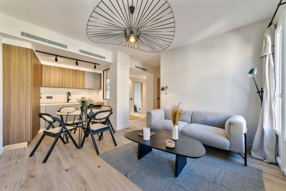 Living and dining room with open kitchen and oak floor, 2-bedroom apartment in the Carré d’Or, Nice