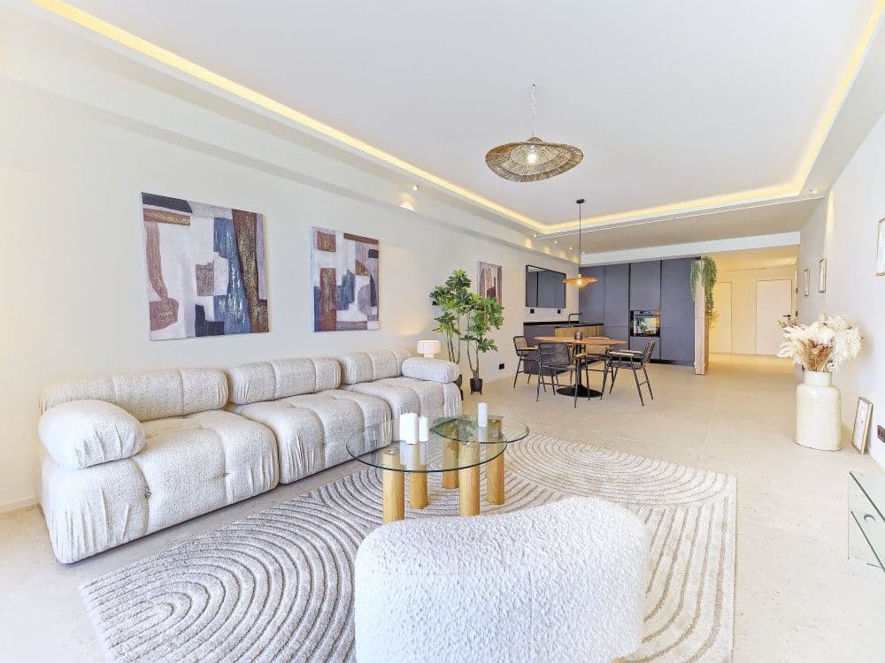 Living room with bouclé sofa and the dining area beyond, 2-bedroom apartment in the Promenade des Anglais, Nice