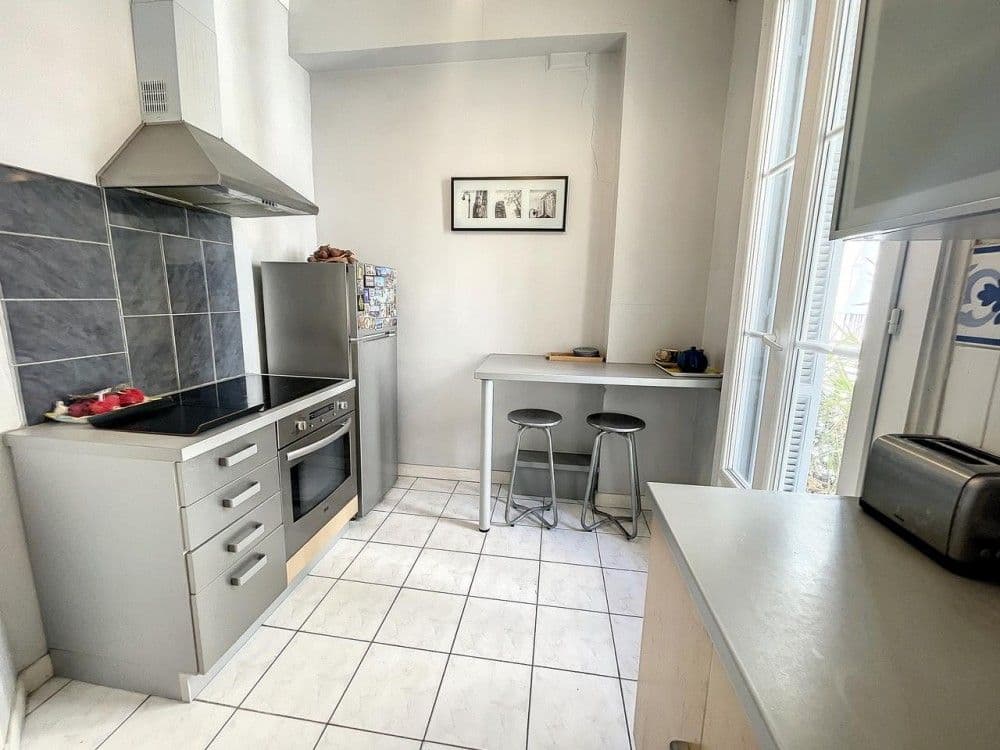 Kitchen with white tiled floor and breakfast bar, 2-bedroom apartment in the Carré d’Or, Nice