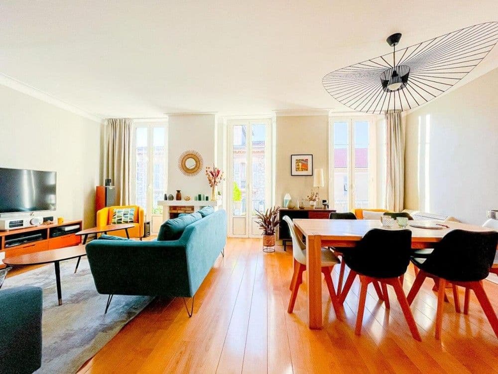 Living and dining room with wooden floor and tall windows, 2-bedroom apartment in central Nice