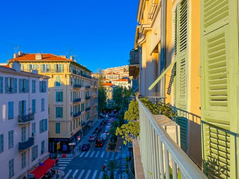 Balcony with green shutters and a view down a tree-lined street, 2-bedroom apartment in central Nice